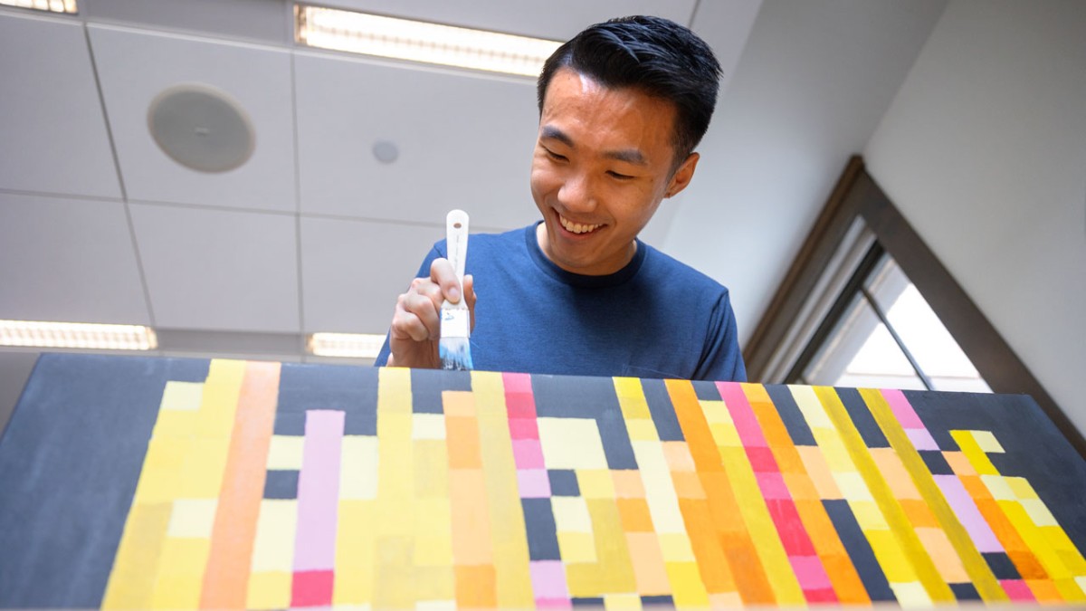 Justin Chen ’24, an environment and sustainability major, paints the edges of his canvas black. His final project is an abstract data visualization that represents the rarity of bird species, conservation status by state and seasonality. 